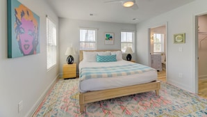 A bedroom with a bed, a ceiling fan, and artwork on the walls.