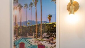 A framed painting of a poolside scene with chairs and palm trees.
