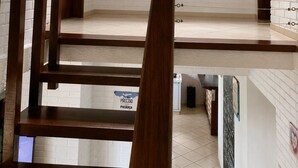 A staircase with wooden handrails leading to a landing with a view of greenery outside. - 5to Elemento House (Búzios)