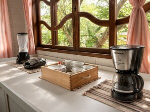A kitchen counter with a coffee maker, a blender, and a wooden mug tray with cups. - 5to Elemento House (Búzios)