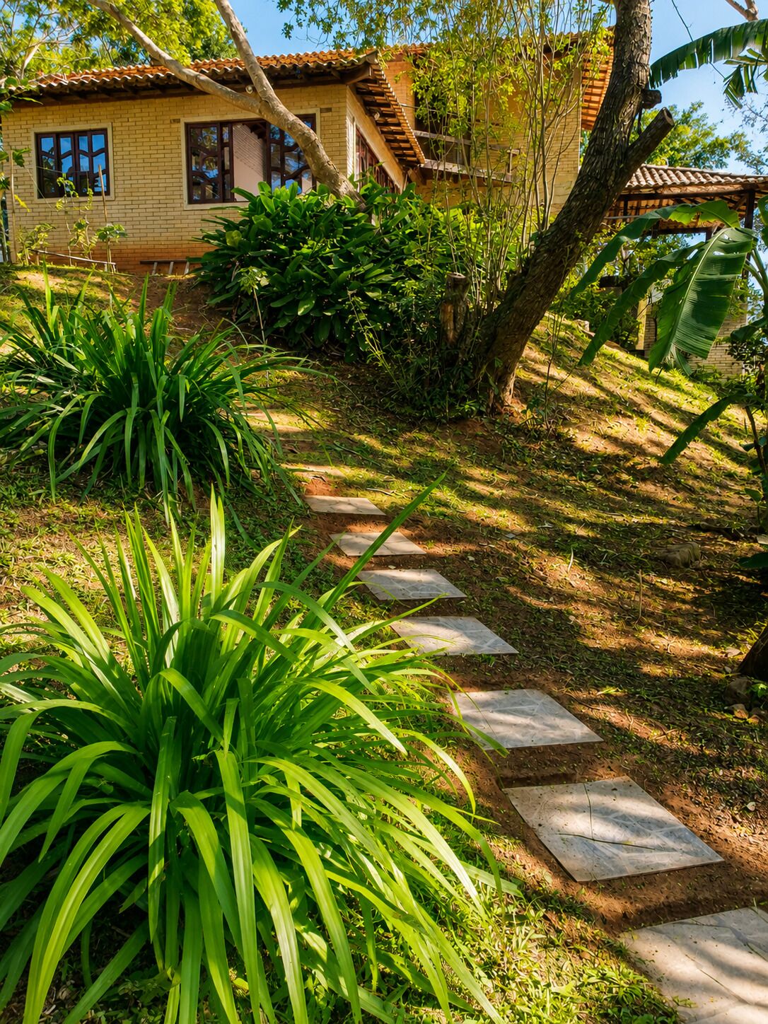 A garden pathway leading to a house with a tiled roof and brick walls.