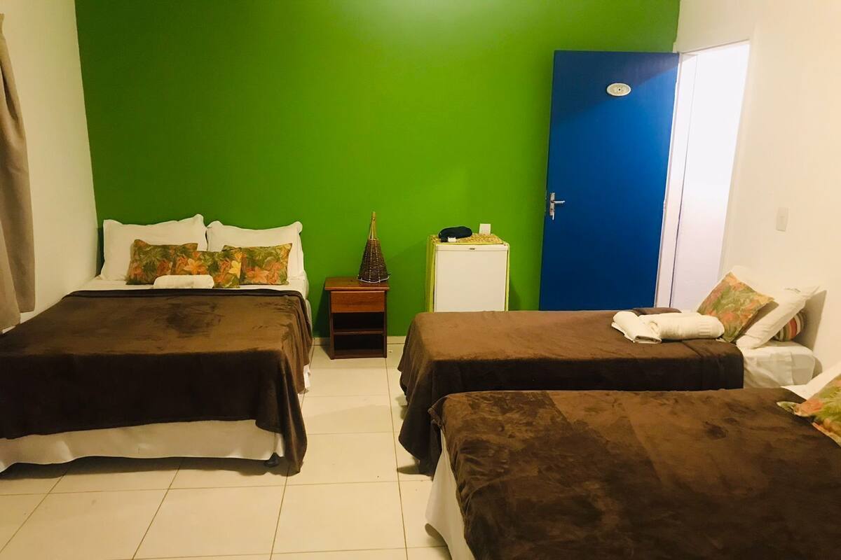 Ein Zimmer mit zwei Betten, einer grünen Wand, einer blauen Tür und einem kleinen weißen Schrank.