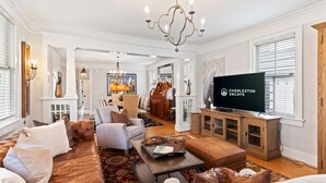 A spacious living room with a large television, comfortable seating, and a fireplace. - Entire 4 Bedroom Historic Charleston House (Charleston)