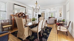 A spacious dining area with a wooden table and chairs, a chandelier, and a large mirror. - Entire 4 Bedroom Historic Charleston House (Charleston)