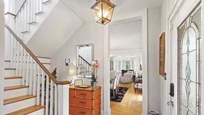 A staircase with white railings and wooden steps leading to a room with a large mirror, a dresser, and a vase of flowers. - Entire 4 Bedroom Historic Charleston House (Charleston)
