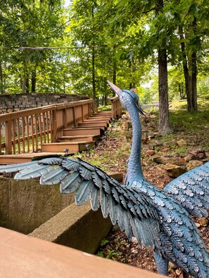 A large bird sculpture with outstretched wings, set against a backdrop of a wooden bridge and trees. - Cozy LOTO retreat! Main channel, 2 decks & dock. Dog friendly & No Cleaning fee! (Sunrise Beach)