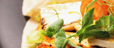 Ein Teller mit drei Tacos, gefüllt mit gegrilltem Hähnchen, Salat und Tomatenscheiben.