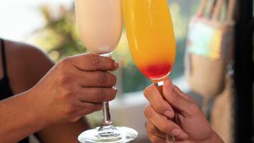Two people holding cocktail glasses with fruit garnishes.