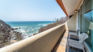 A balcony with a view of the ocean, white chairs, and a textured wall. - Villas Coral Huatulco (Santa María Huatulco)