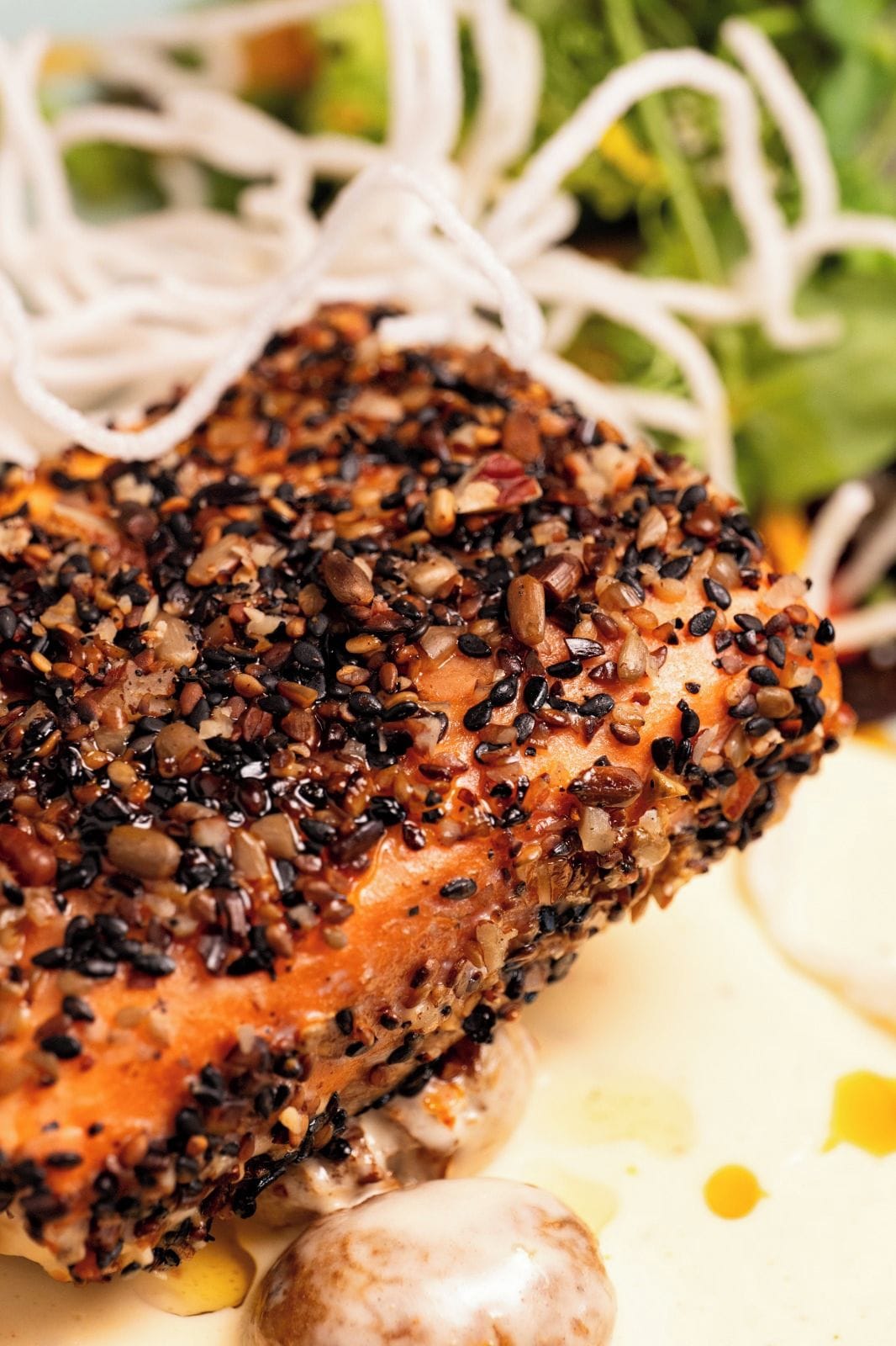 A close-up of a seasoned steak with a variety of seeds and spices on top.