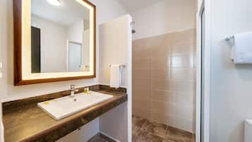 Un baño moderno con un espejo grande, un lavabo y una zona de ducha.