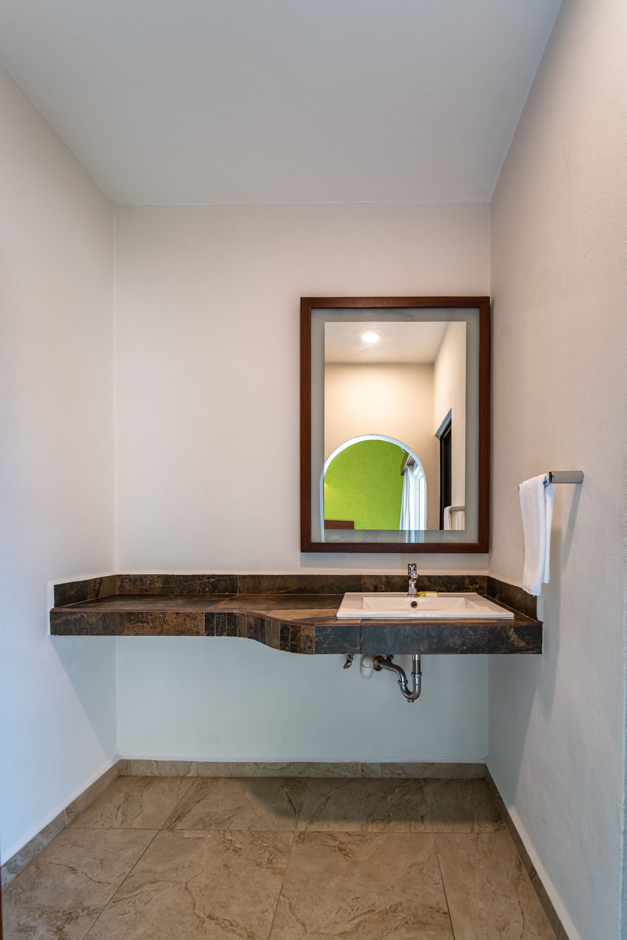 A bathroom with a white sink, a mirror, and a towel rack.