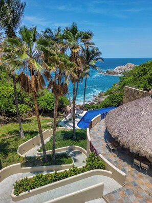 A resort with a pool area, palm trees, and a view of the ocean. - Villas Coral Huatulco (Santa María Huatulco)