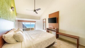 A bedroom with a bed, a desk, a TV, and a view of the ocean. - Villas Coral Huatulco (Santa María Huatulco)