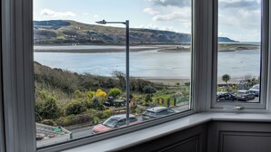 A view from a window overlooking a coastal area with a road, parked cars, and a lamp post. - 2 bedroom accommodation in Barmouth (Barmouth)
