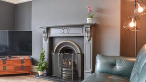 A modern living room with a fireplace, leather sofa, and a flat-screen TV. - 2 bedroom accommodation in Barmouth (Barmouth)
