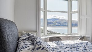 A bedroom with a large bay window overlooking a scenic landscape. - 2 bedroom accommodation in Barmouth (Barmouth)