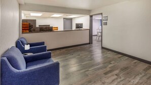 A reception area with a reception desk, a computer, and a seating area with blue chairs. - Baymont by Wyndham Laredo (Laredo)