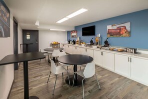A modern kitchen with white cabinets, a black countertop, and a round dining table with white chairs. - Baymont by Wyndham Laredo (Laredo)