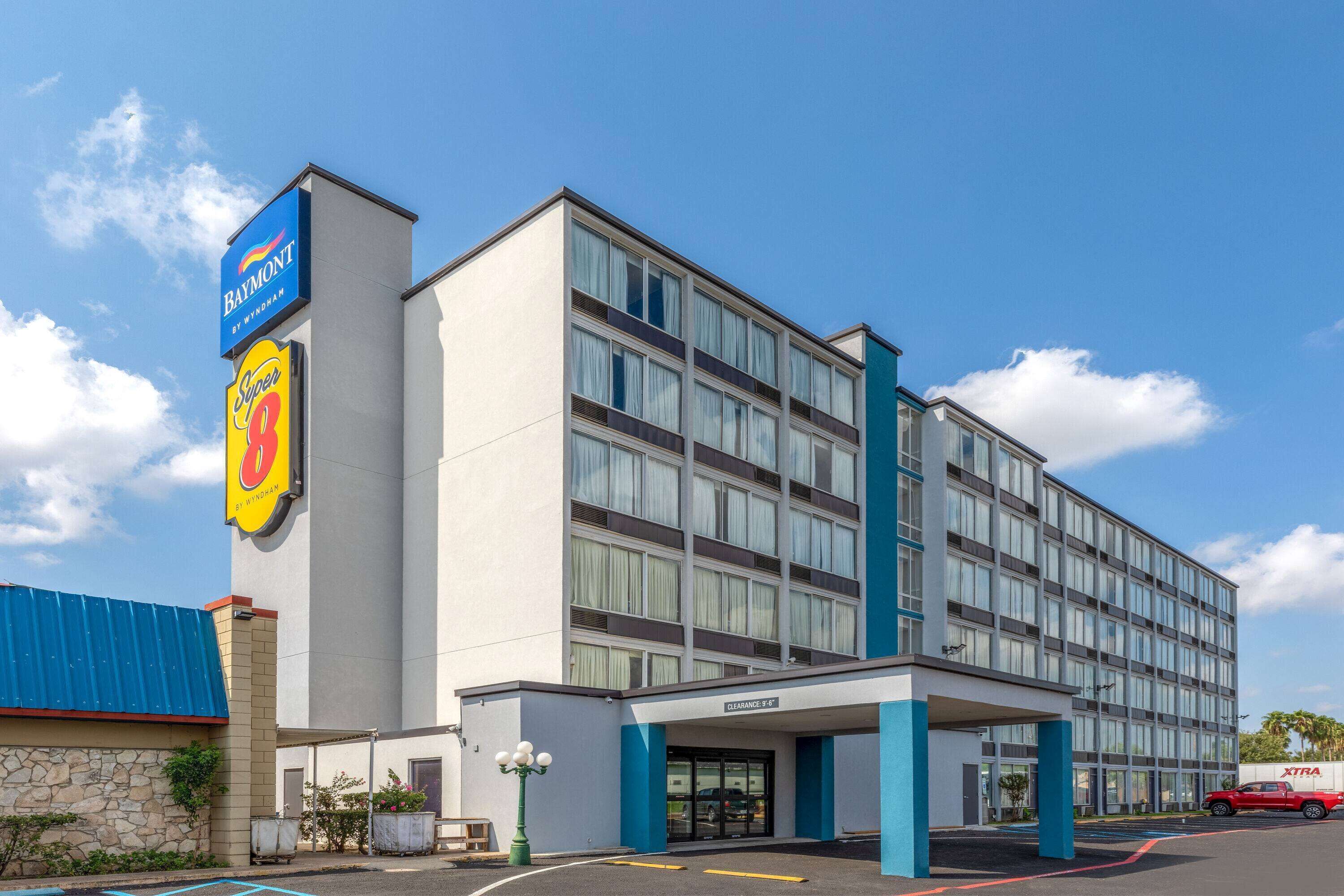 Un hôtel à plusieurs étages, doté d’une entrée bien visible, d’une enseigne indiquant un restaurant à proximité et d’un parking.