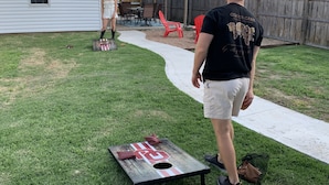 Patio con una mesa de madera, un objetivo de metal y una persona de pie.