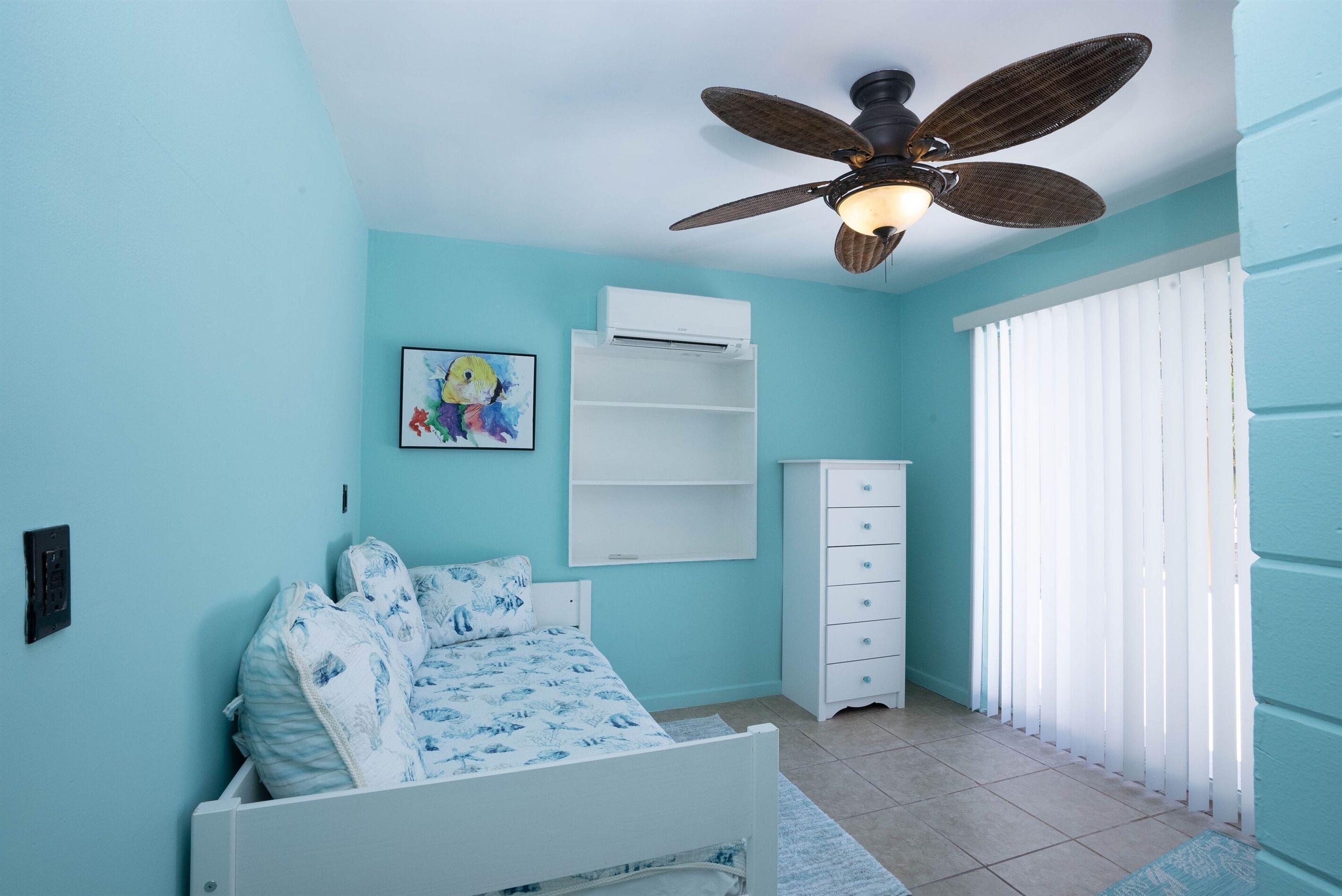 A bedroom with a bed, a ceiling fan, a white dresser, and a window with blinds.