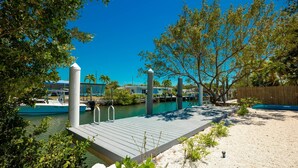 A dock extending into a calm body of water, surrounded by greenery and a clear blue sky. - Gorgeous 3/2 SFH brand-new pool & spa,30ft dockage (Marathon)
