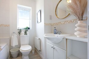 A bathroom with a toilet, bidet, sink, mirror, and radiator.
