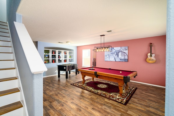 Ein geräumiger Raum mit Billardtisch, Kicker und Gitarre an der Wand.