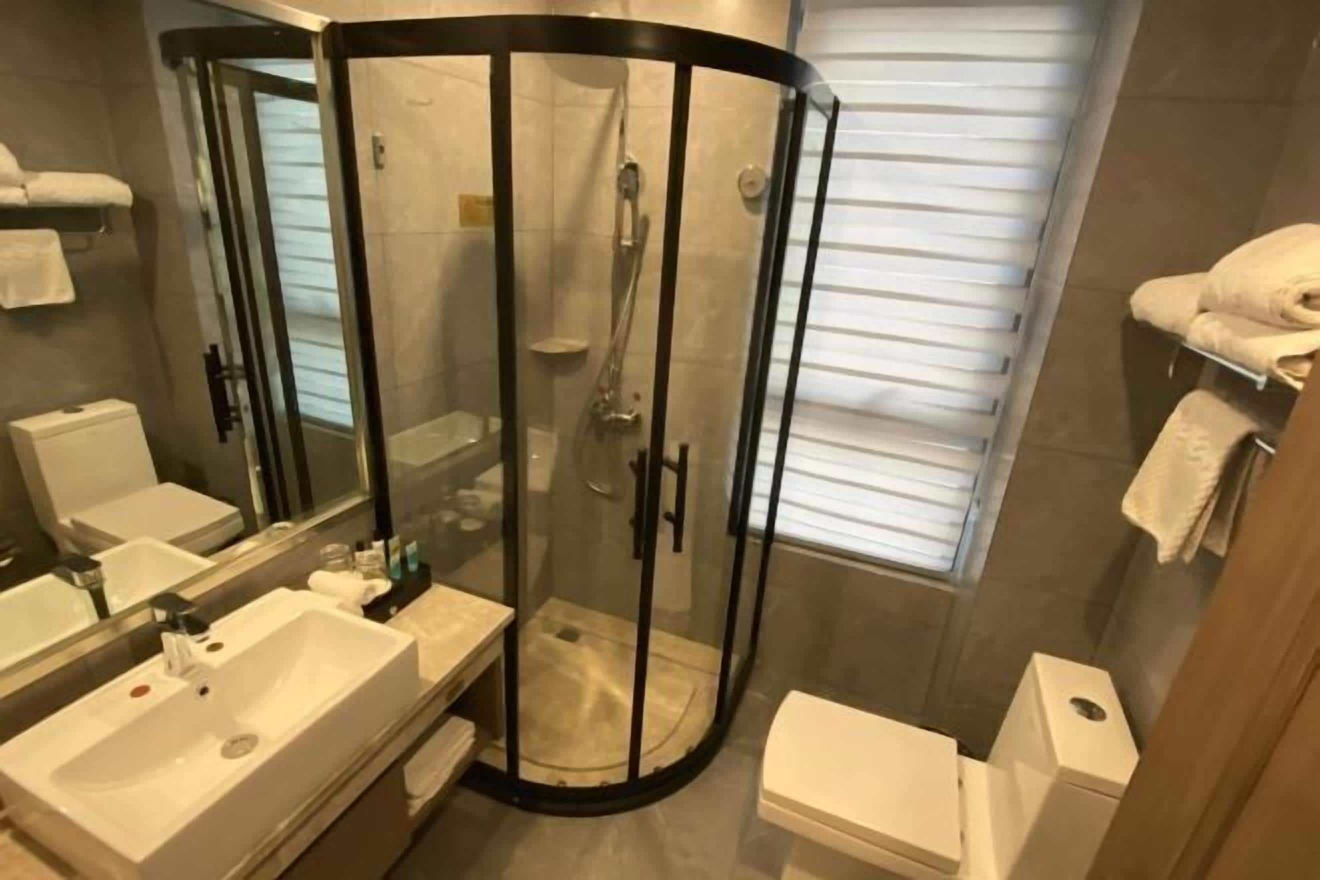 Ein modernes Badezimmer mit einer Duschkabine, einem Waschbecken, einer Toilette und einem Spiegel.