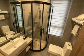A modern bathroom with a glass-enclosed shower, a sink, a toilet, and a mirror. - Dongyuan Hotel (Yangzhong)