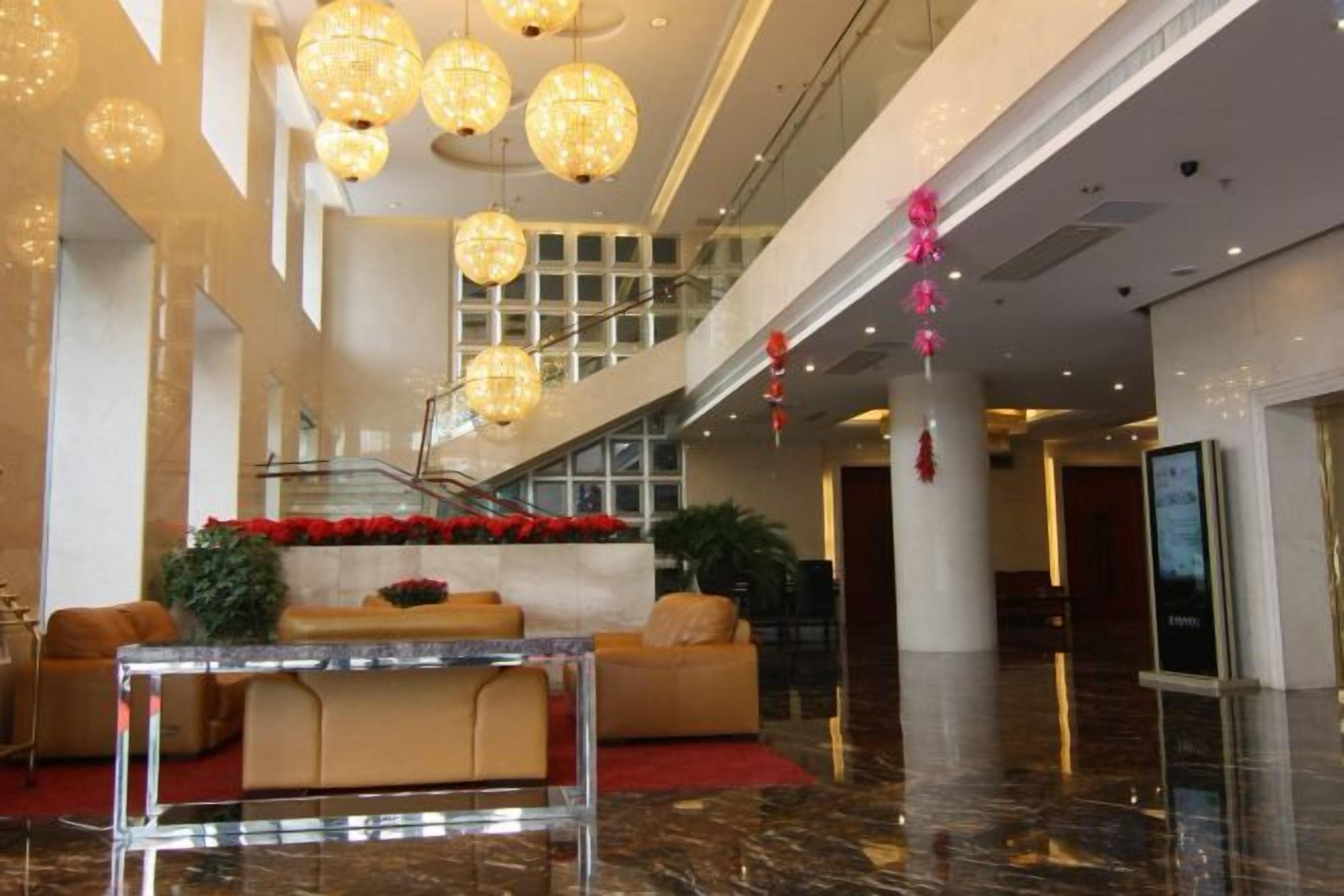 A lobby with a marble floor, a reception desk, and a staircase.