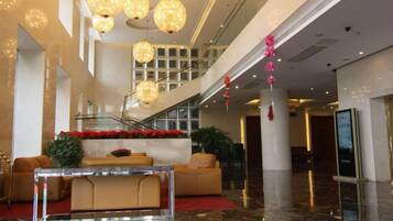 A lobby with a marble floor, a reception desk, and a staircase.