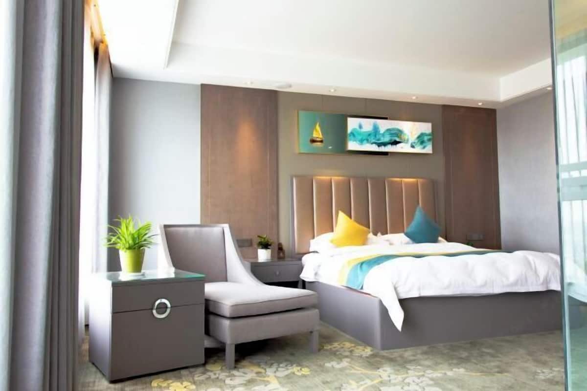 Quarto moderno com cama, mesa de cabeceira, cadeira e obra de arte na parede.