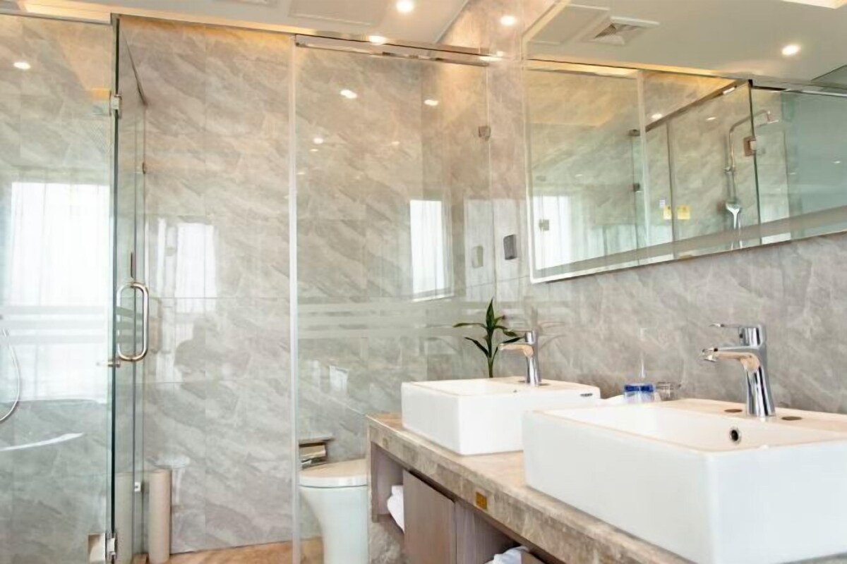 A modern bathroom with a glass shower enclosure, two sinks, and a large mirror.