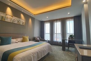 A modern hotel room with a large bed, a desk, and a seating area. - Dongyuan Hotel (Yangzhong)