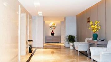 Un hall d’hôtel avec un sol en marbre, un comptoir d’accueil et un espace salon.