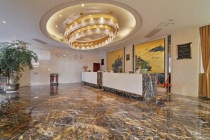 A hotel lobby with a marble floor, a reception desk, a large chandelier, and a painting on the wall. - Dongyuan Hotel (Yangzhong)