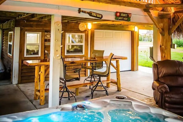 Un espace extérieur aménagé en bois, comprenant un coin salon avec un jacuzzi, une table et des chaises.