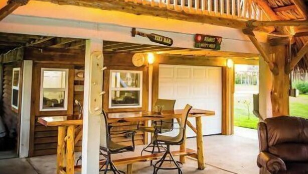 A wooden cabin with a hot tub, a dining area, and a balcony. - Private Hot Tub with outdoor shower and tiki area to relax and Enjoy! (Galveston)
