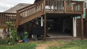 A wooden deck with a thatched roof and a staircase leading to an upper level. - Private Hot Tub with outdoor shower and tiki area to relax and Enjoy! (Galveston)