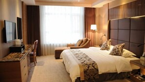 A hotel room with a bed, a desk, a chair, a TV, and a window with curtains. - Hui Nan Hotel (Huinan)