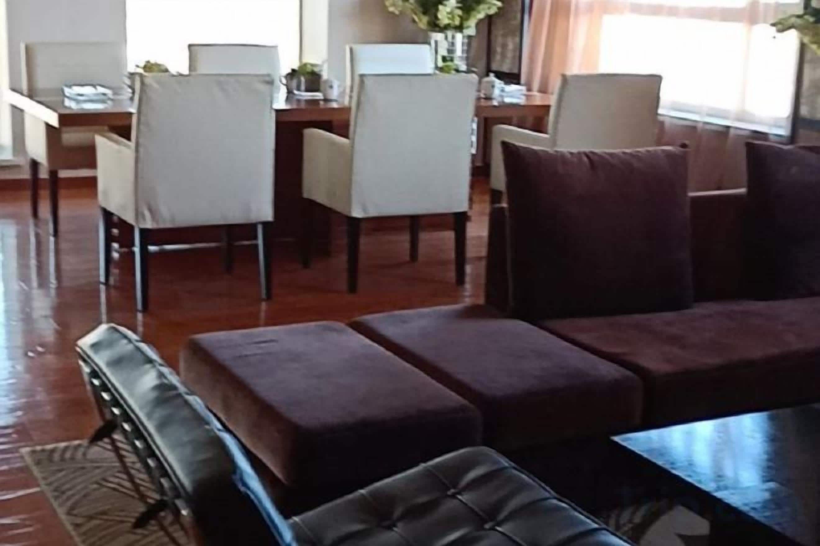 A living room with a sofa, a coffee table, and a dining area with chairs and a table.