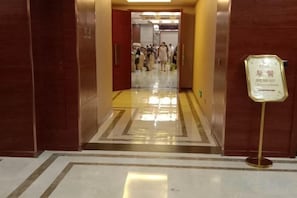 A corridor with a polished floor, a sign indicating a breakfast area, and a group of people in the distance. - Hui Nan Hotel (Huinan)