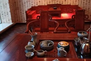 Une table à manger traditionnelle en bois, accompagnée d’un ensemble d’ustensiles à thé, comprenant des tasses, une théière et une bouilloire.