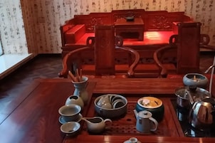 Una mesa de comedor de madera tradicional con un juego de utensilios para té, incluyendo tazas, tetera y hervidor.
