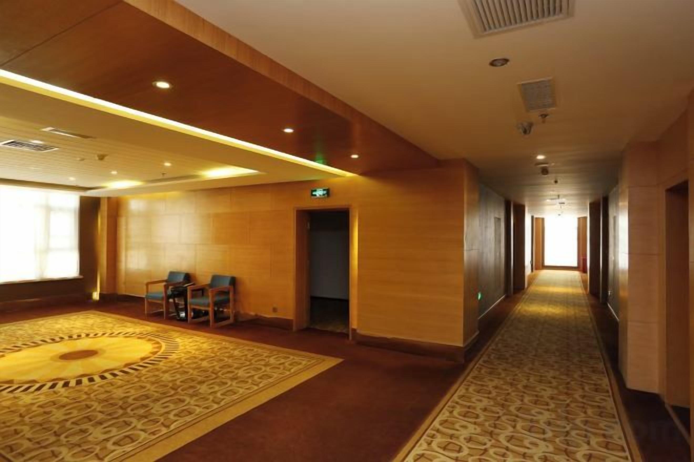 Un pasillo de hotel con suelo alfombrado, paredes de madera y una puerta al final.