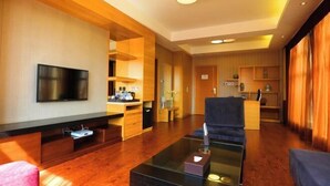 A modern hotel room with a flat-screen TV, a glass coffee table, a sofa, and a kitchen area. - Hui Nan Hotel (Huinan)