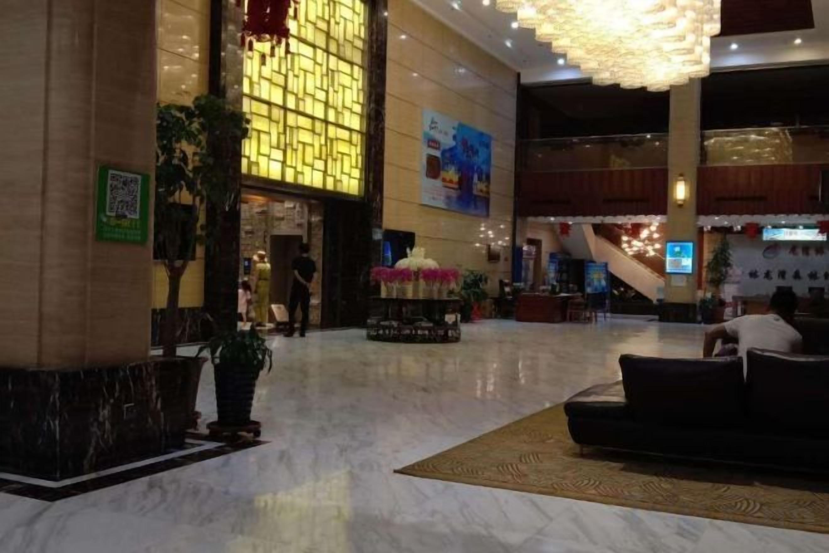A spacious lobby with a marble floor, a reception desk, and a staircase in the background.