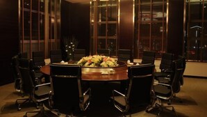 A conference room with a round table, black chairs, and a floral centerpiece. - Hui Nan Hotel (Huinan)